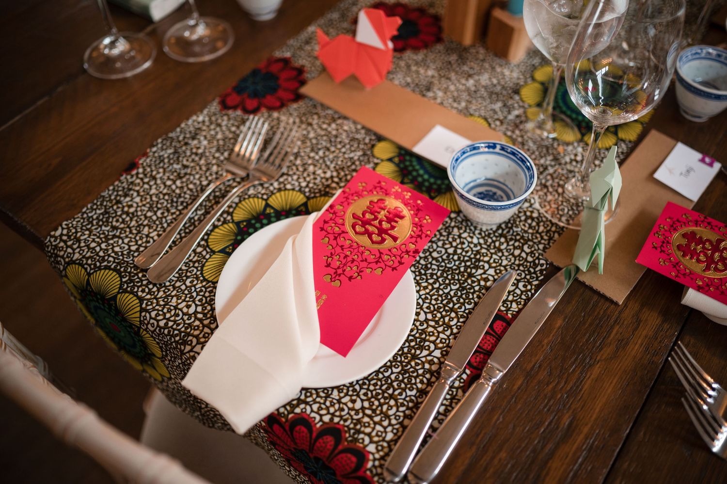 Wedding reception table decorated with red flowers, leopard print details, and string lights.