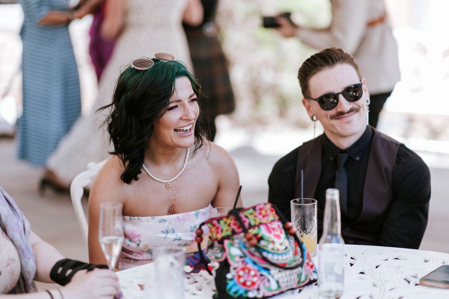 Wedding guests sharing a joyful moment at an outdoor reception table.