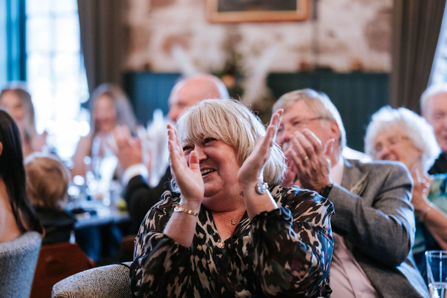 Wedding guests enjoying a reception in a rustic indoor venue.