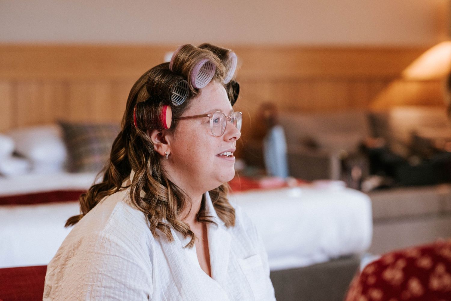 A person getting ready on wedding morning wearing white robe and hair curlers.