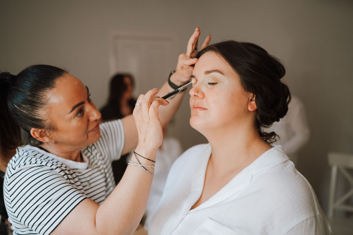 Makeup application in process with professional tools and white robe.
