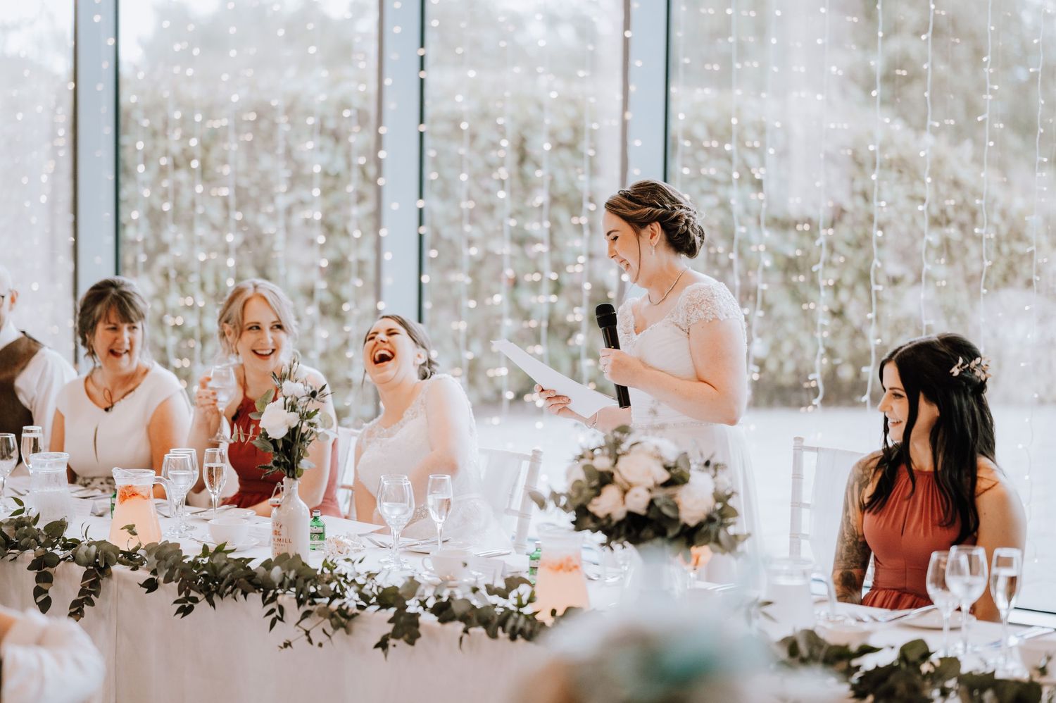 Celebration at a bright wedding venue with festive table decorations and greenery.