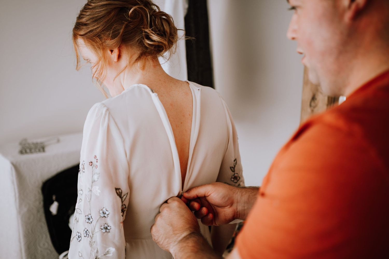 Wedding dress being buttoned up showing intricate detail on back.