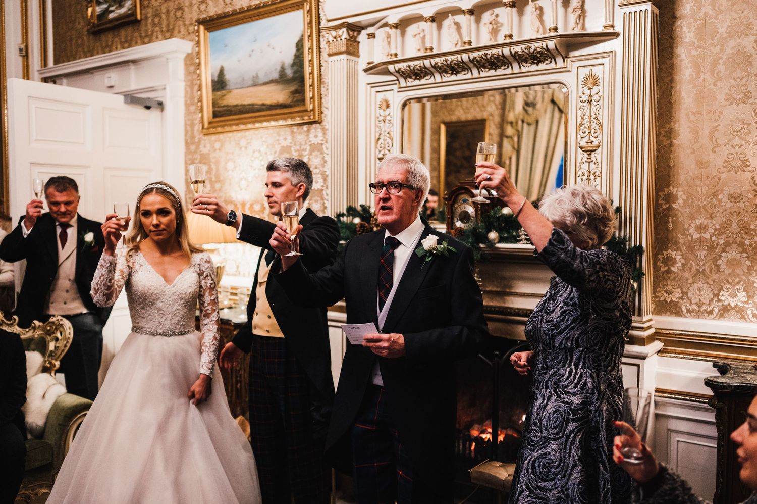 Wedding attendees gather in an ornate room with classical paintings and architectural details.