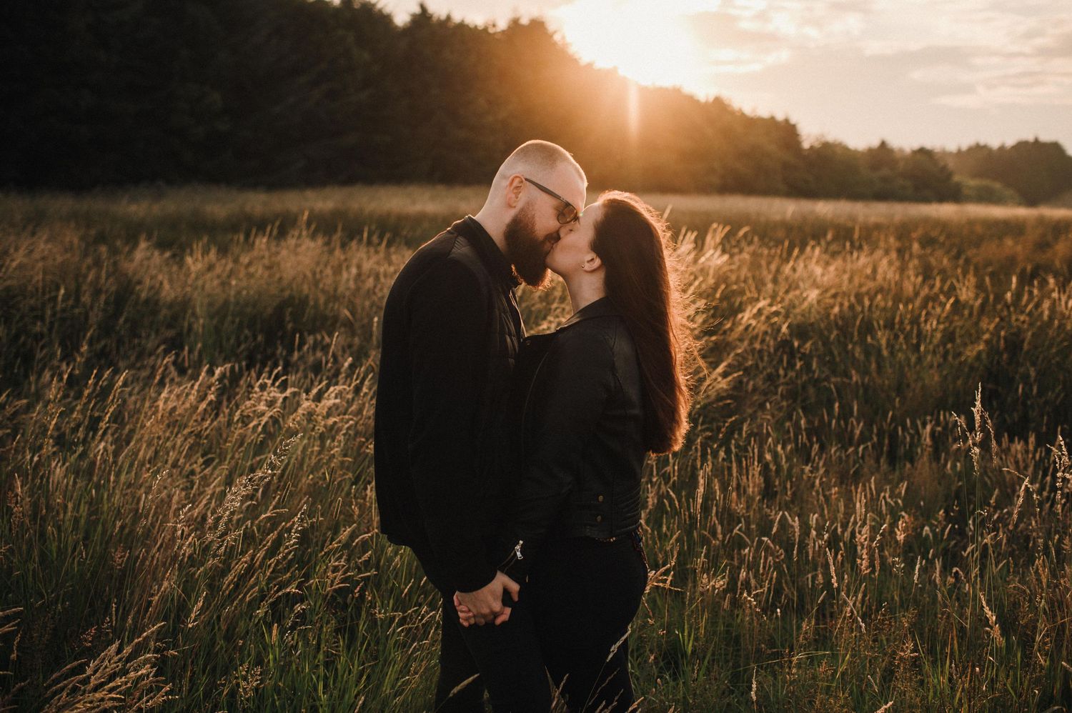 A romantic sunset photoshoot in a golden field with tall grass and warm lighting.