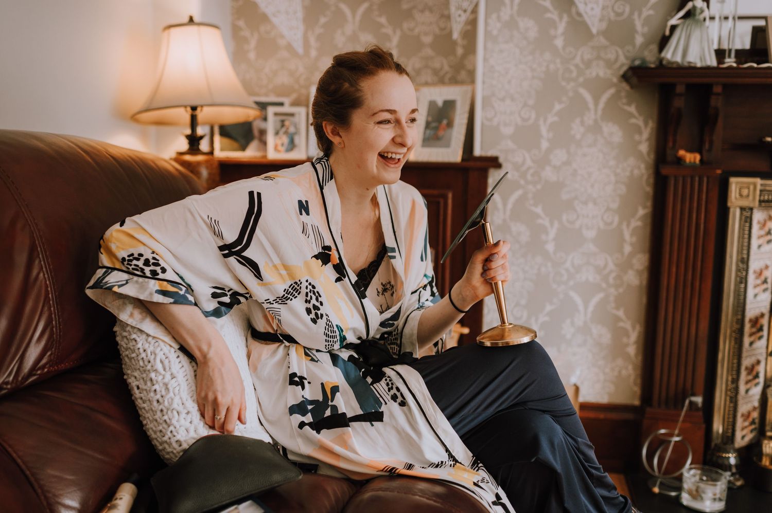 Candid moment of laughter on brown leather couch in cozy living room.