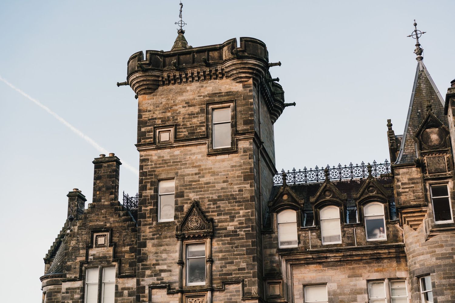 Architectural detail of a Scottish castle tower with ornate stonework against blue sky.