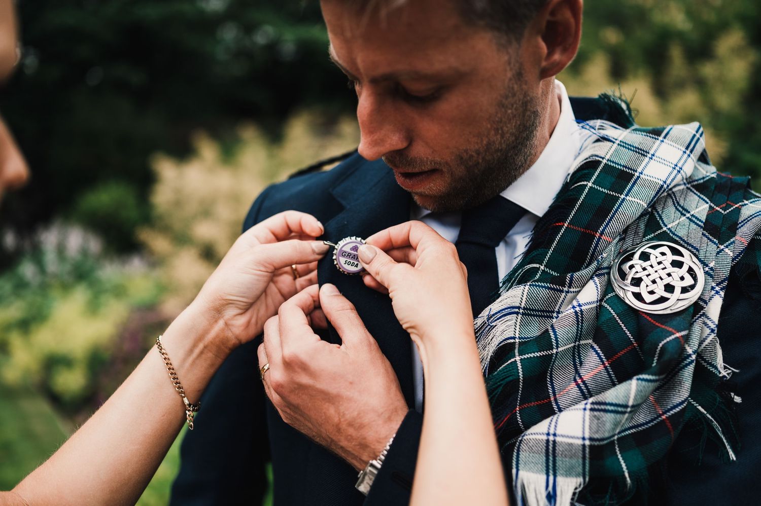 Close up of hands exchanging rings during a Scottish wedding ceremony with traditional tartan visible.