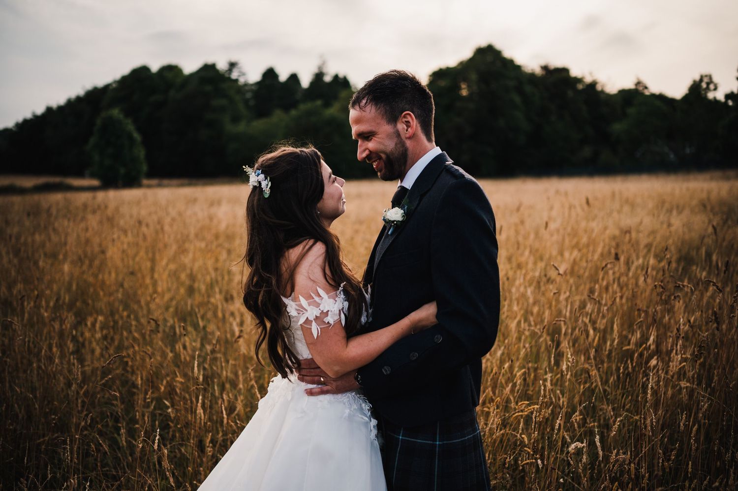 A romantic moment between newlyweds in a sun-lit field.