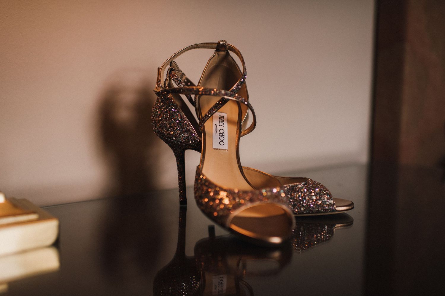 Sparkly bronze high heel sandals with crystal embellishments on dark surface.