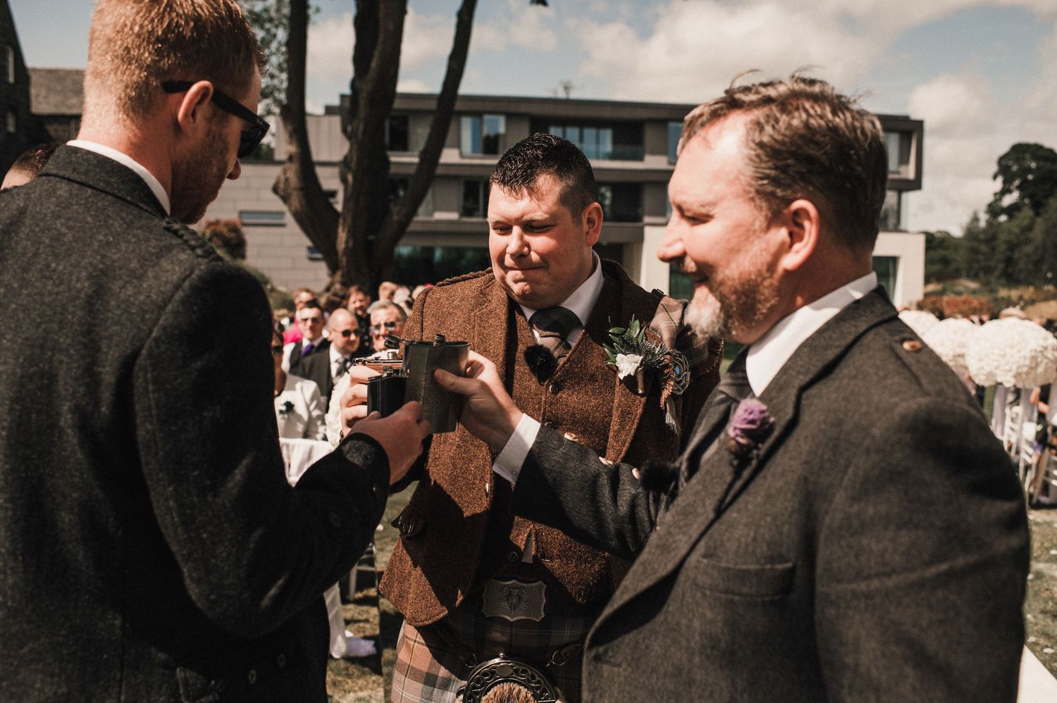 Guests in formal attire clink glasses during an outdoor wedding celebration.