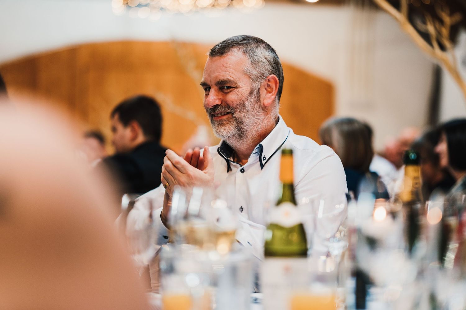Guests enjoying drinks and conversation at an elegant dinner reception with wine glasses on the table.