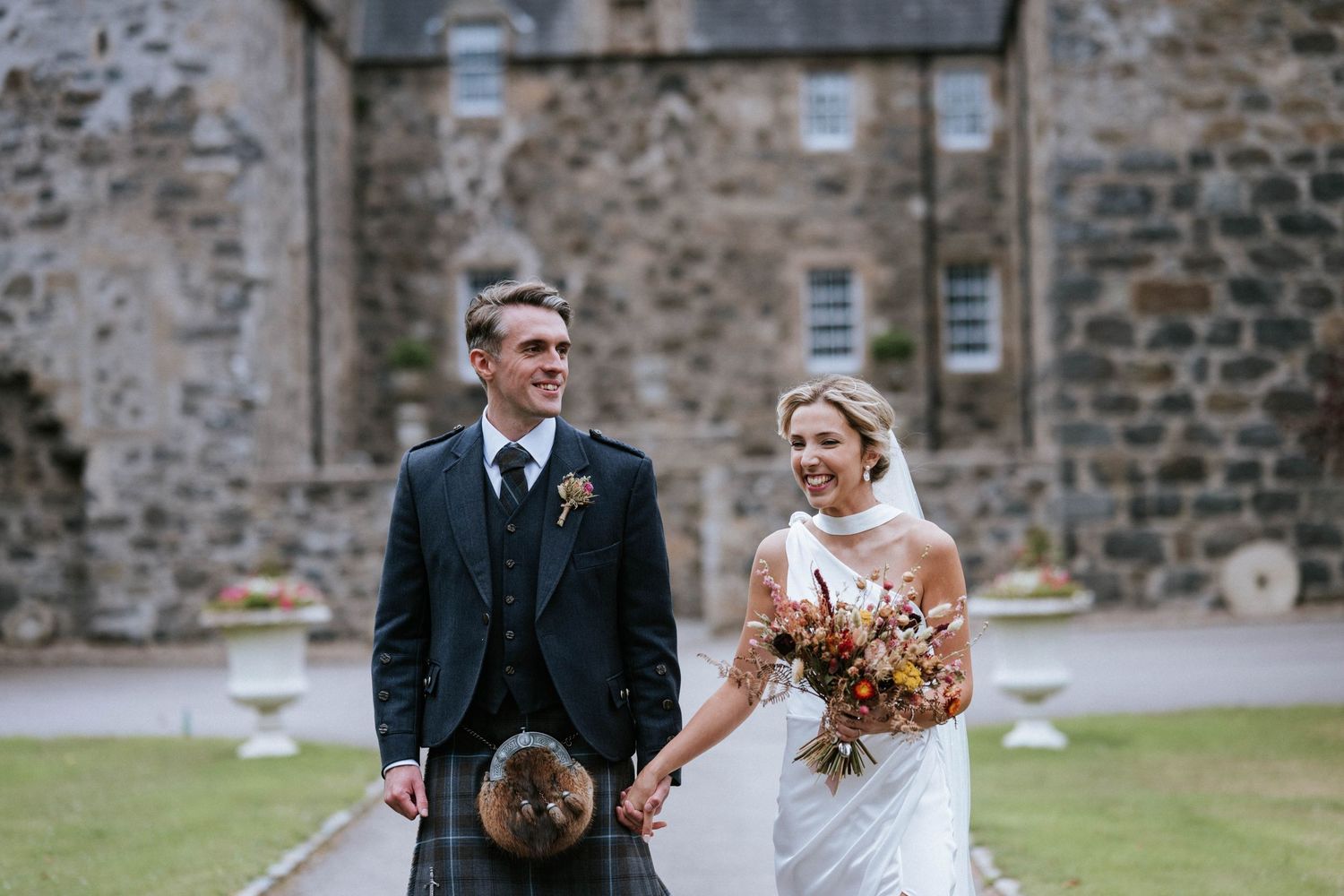 Wedding group photos taken outside a traditional Scottish stone building.