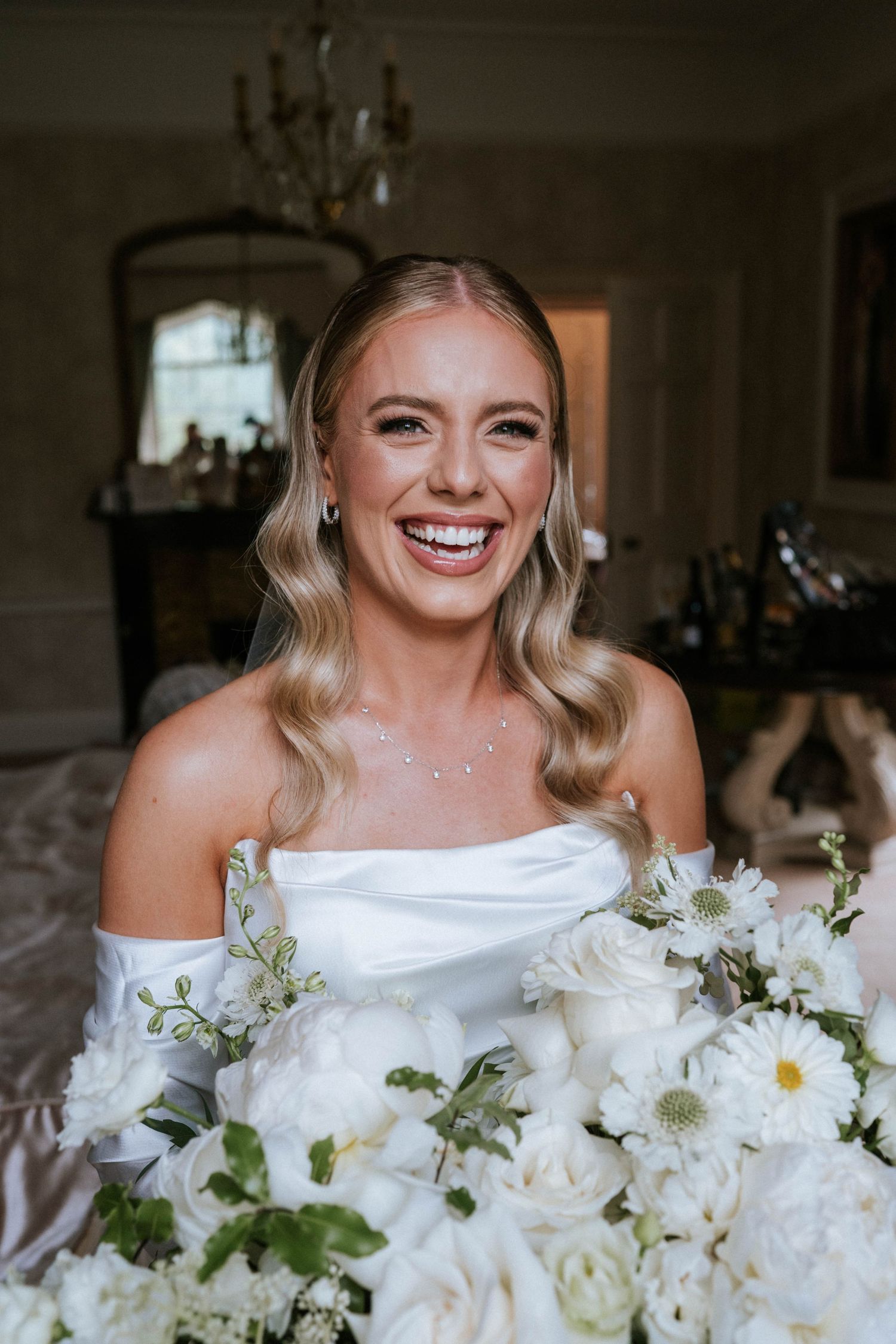 A stunning bridal portrait featuring an elegant white off-shoulder gown and a lush bouquet of white flowers.