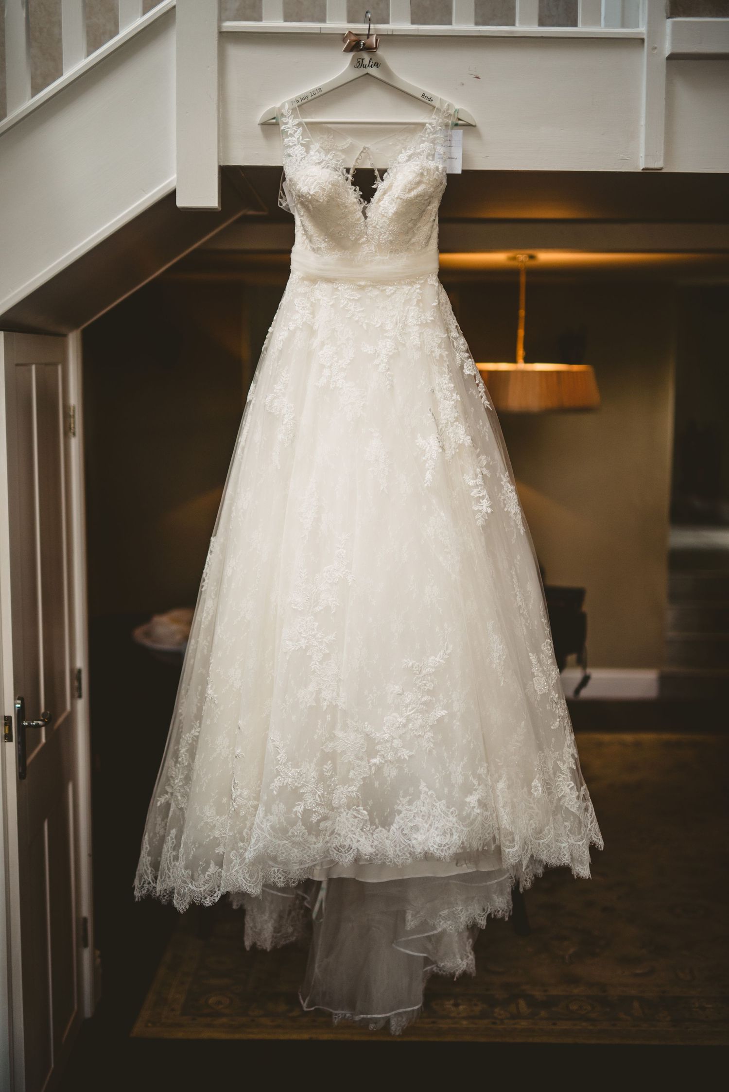 Elegant white lace wedding dress displayed on a hanger in different angles showing intricate details.