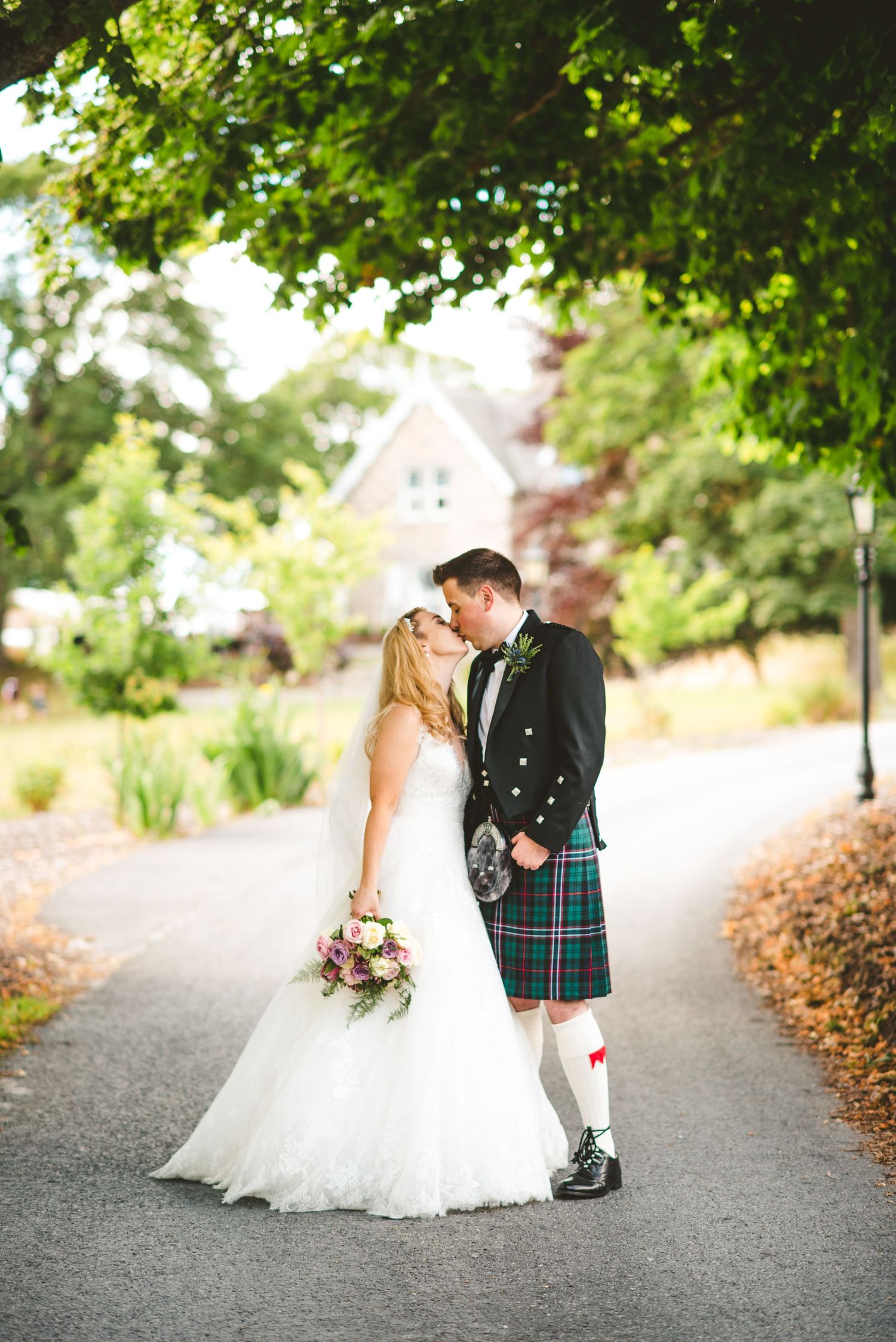 Candid wedding photography moments on a scenic outdoor path with Scottish elements.