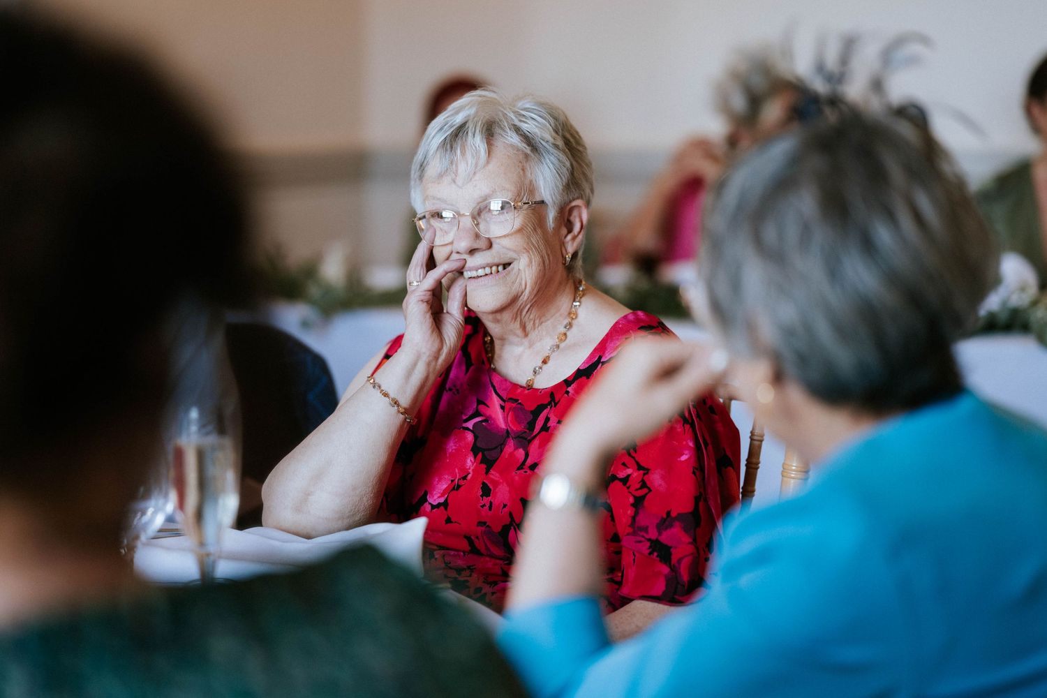 Guest in red dress laughs heartily during wedding reception festivities.