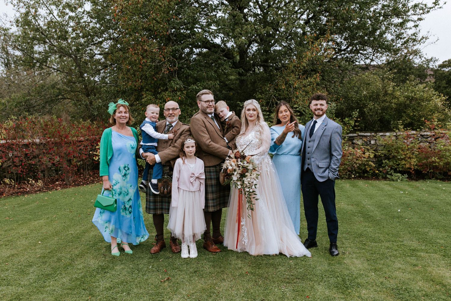 Wedding group photo with family members in mix of formal wear and traditional Scottish attire.