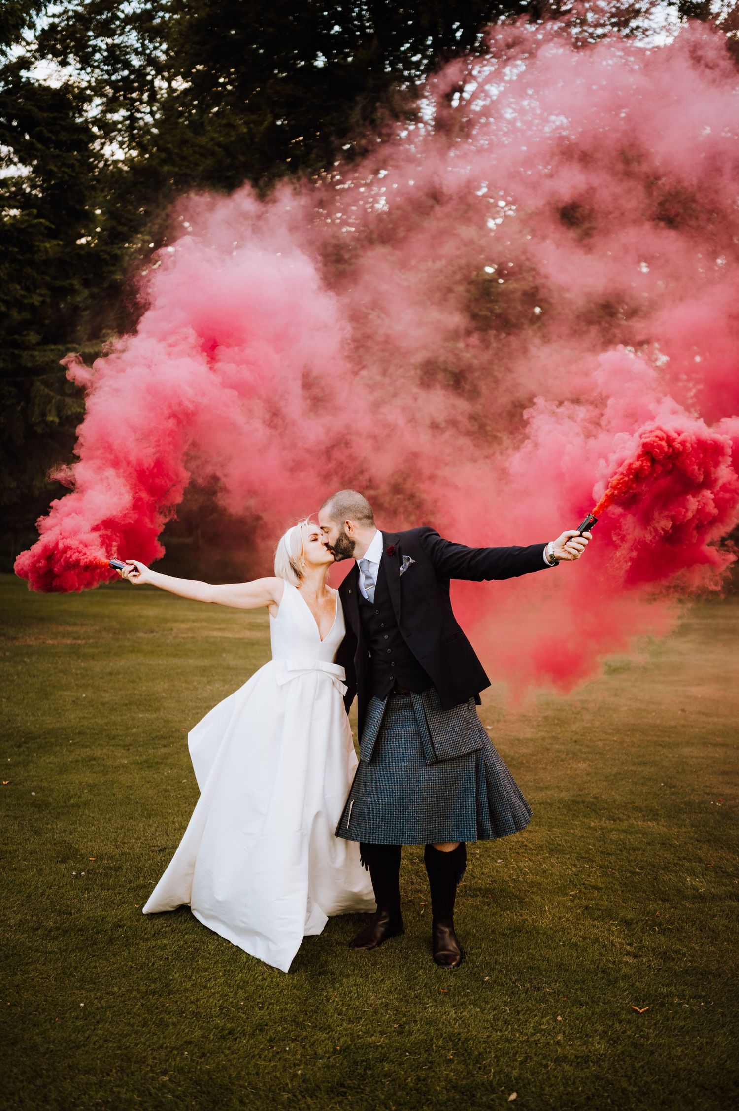 Aberdeen Wedding Photography. Wedding couple poses dramatically with red smoke bombs in outdoor field.