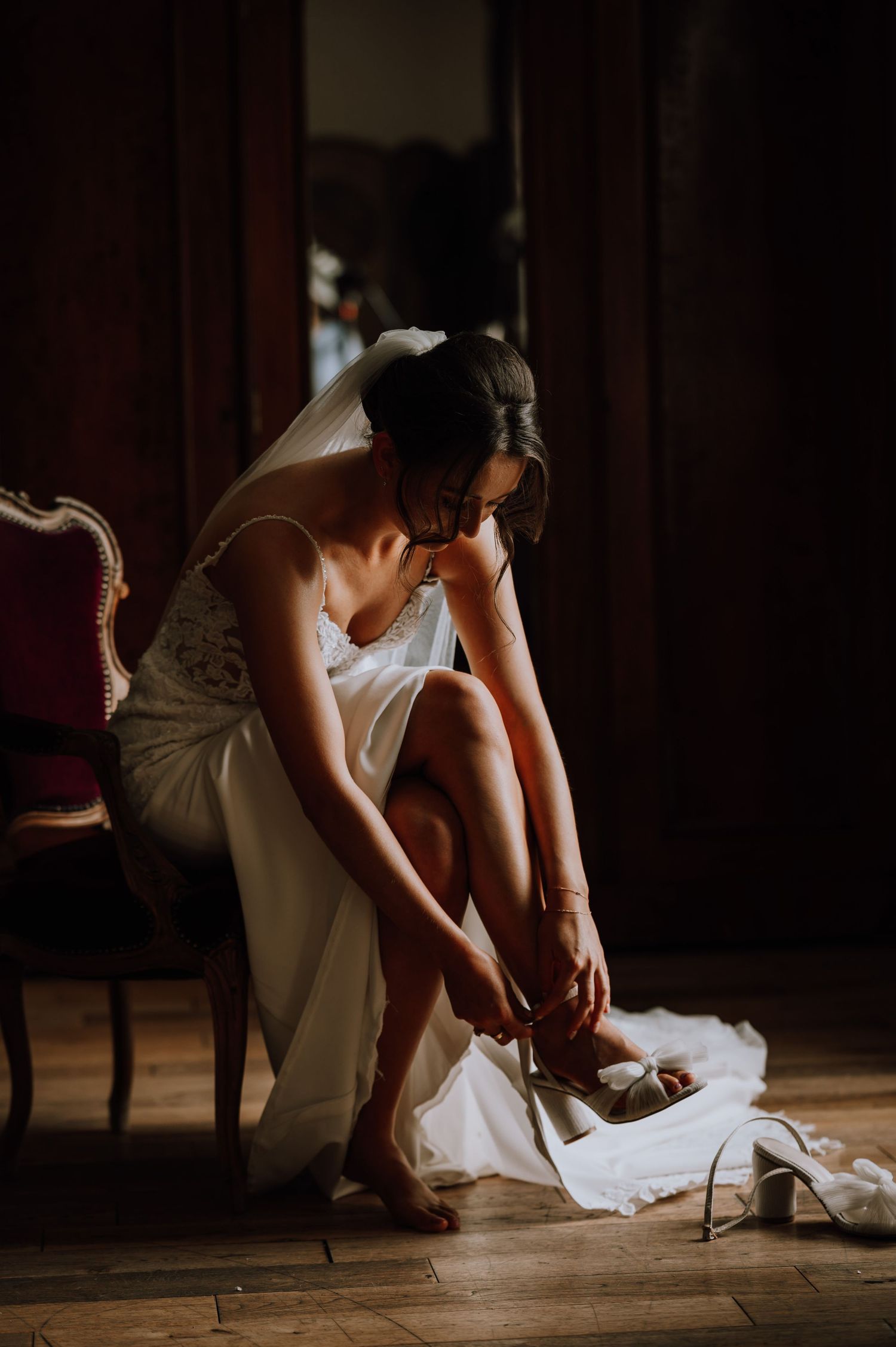 Aberdeen Wedding Photography. Person in white dress sitting and putting on shoes in moody lighting.