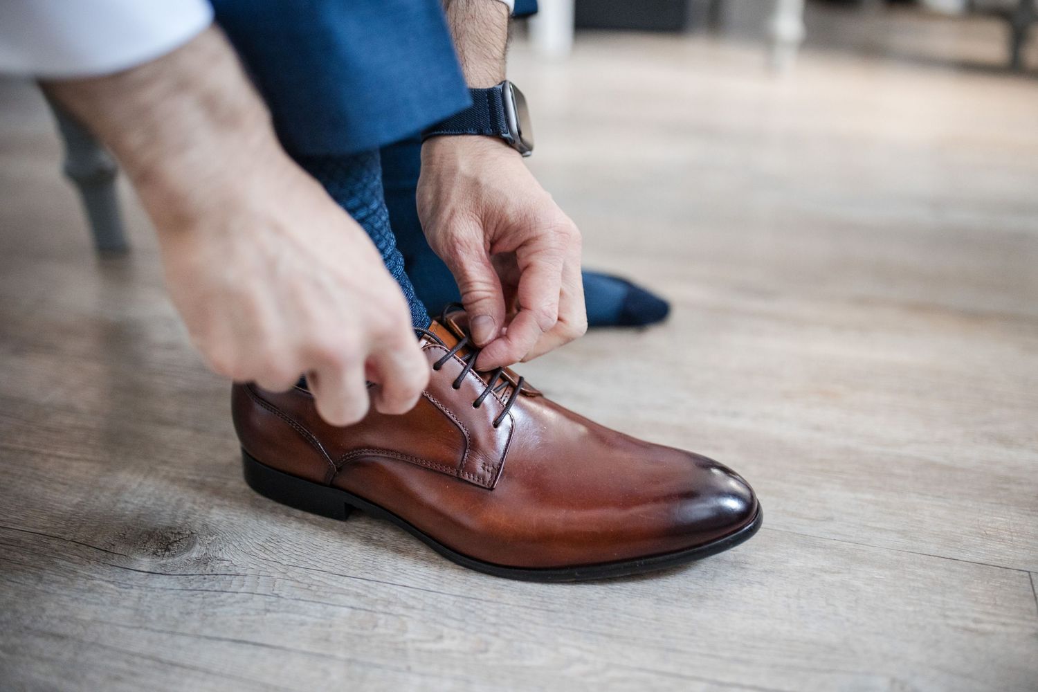 Close-up shots showing brown leather dress shoes being put on and tied.