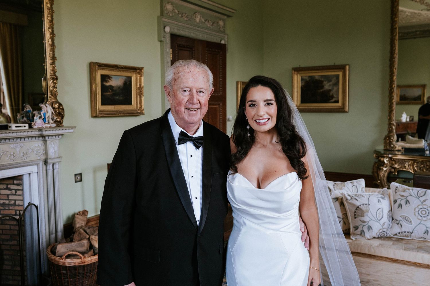 Formal wedding gathering in a stately room with traditional furnishings and artwork.