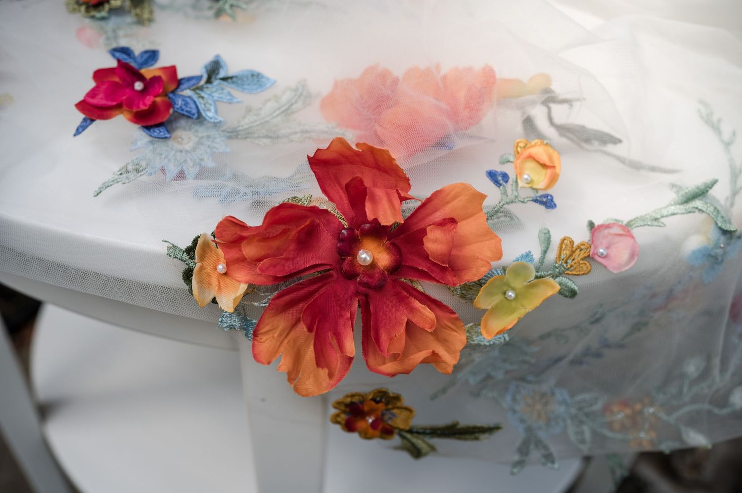 Delicate floral decorations in red, orange and blue arranged on a white surface.