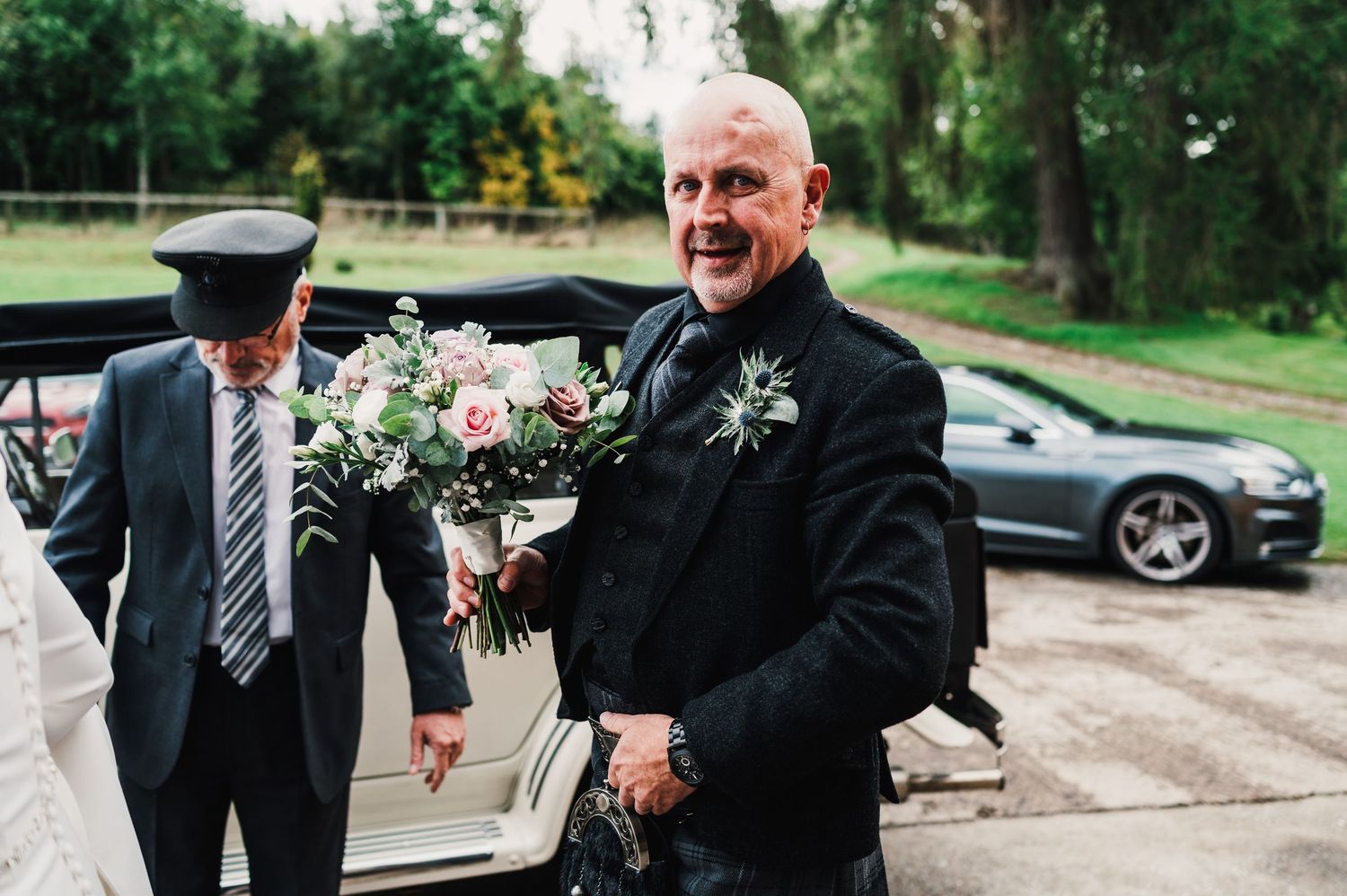 Wedding guests mingling outdoors on a sunny day wearing formal attire.