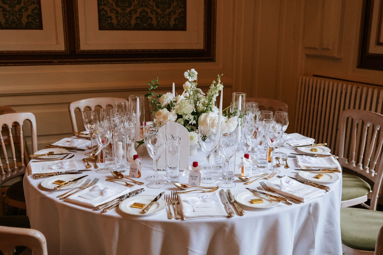 Elegant wedding reception tables set with white linens, crystal glasses and formal place settings.