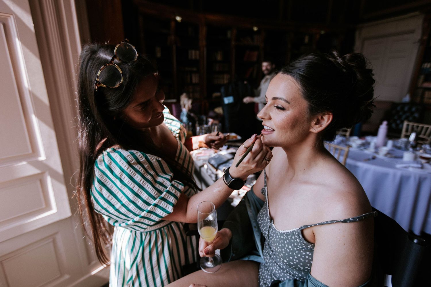 Wedding preparation scene with makeup application in elegant room setting.