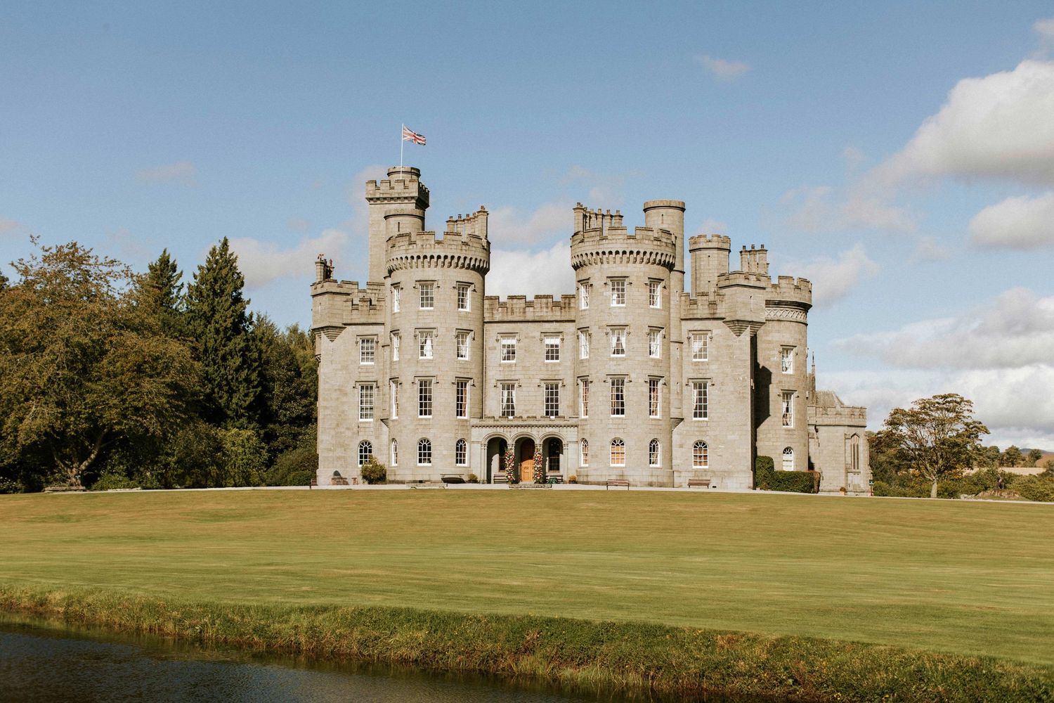 Panoramic view of a grand Scottish castle estate with manicured lawns.