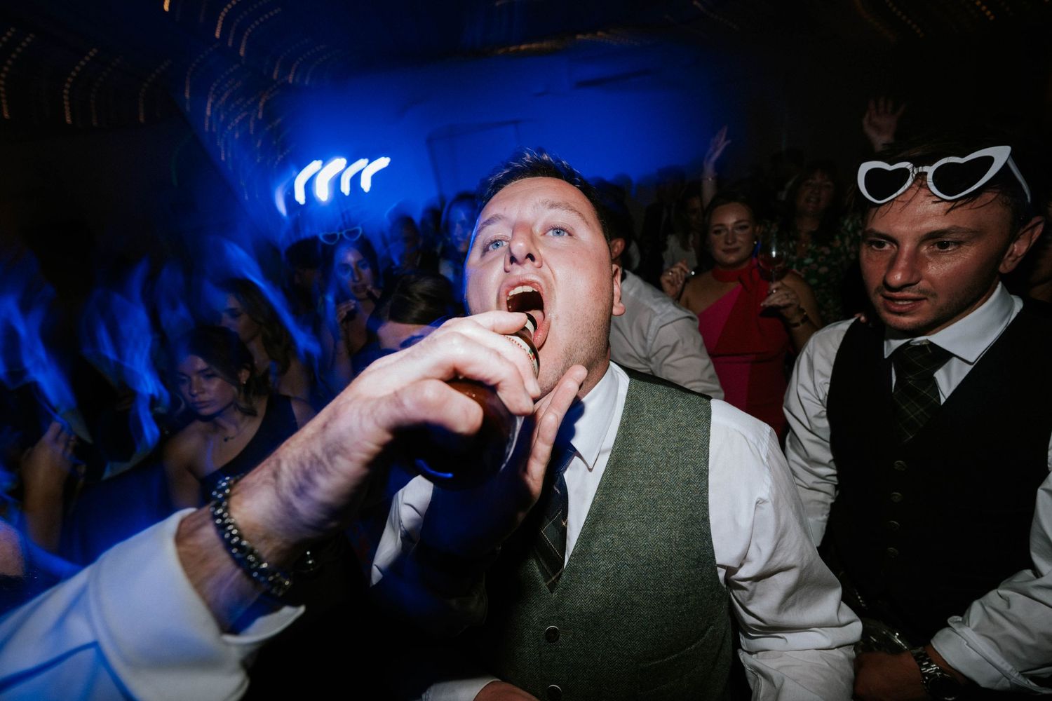 Aberdeen Wedding Photography. Guests dancing and celebrating at a wedding reception with dramatic blue lighting.