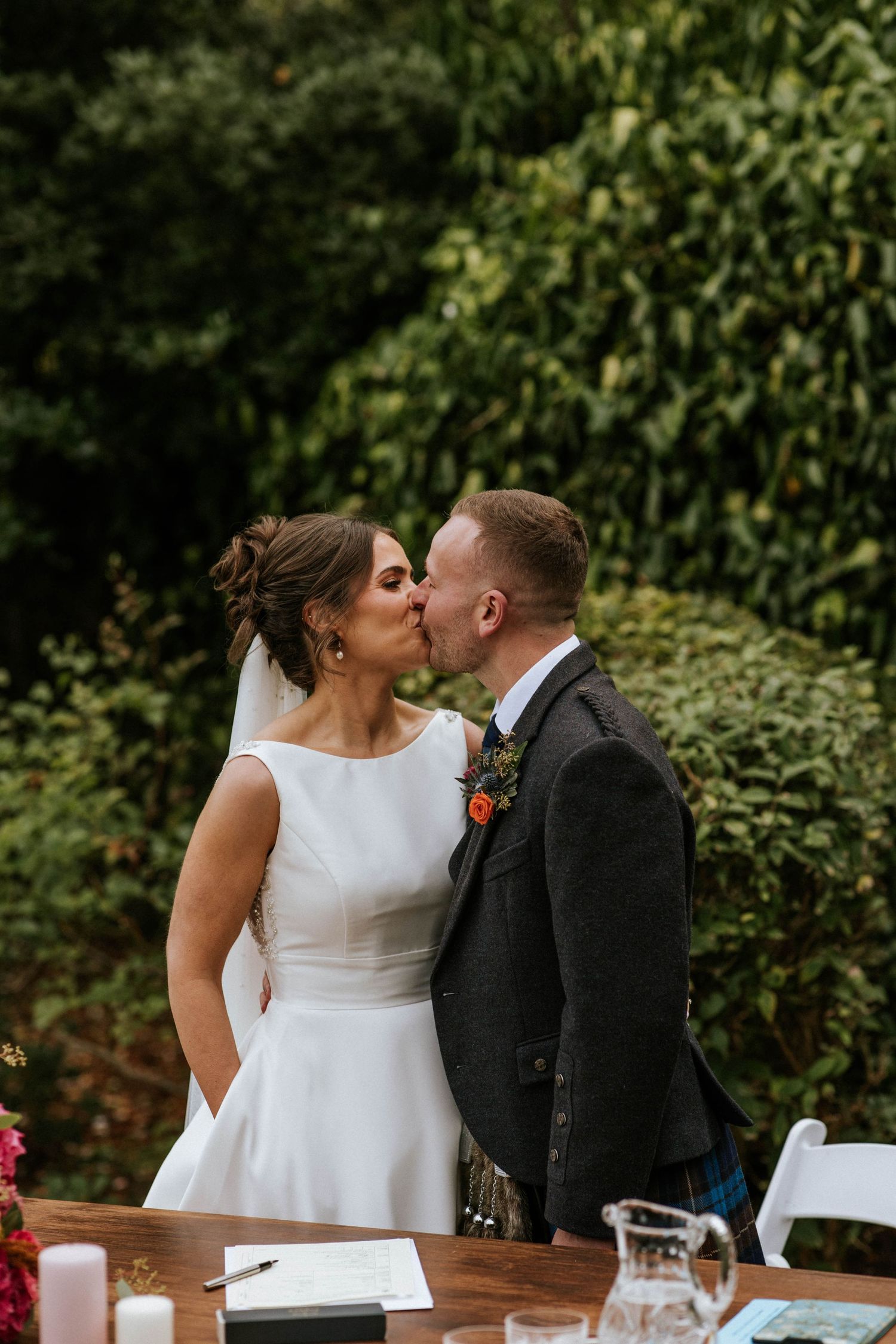 Intimate wedding ceremony moment at a rustic outdoor table setting.