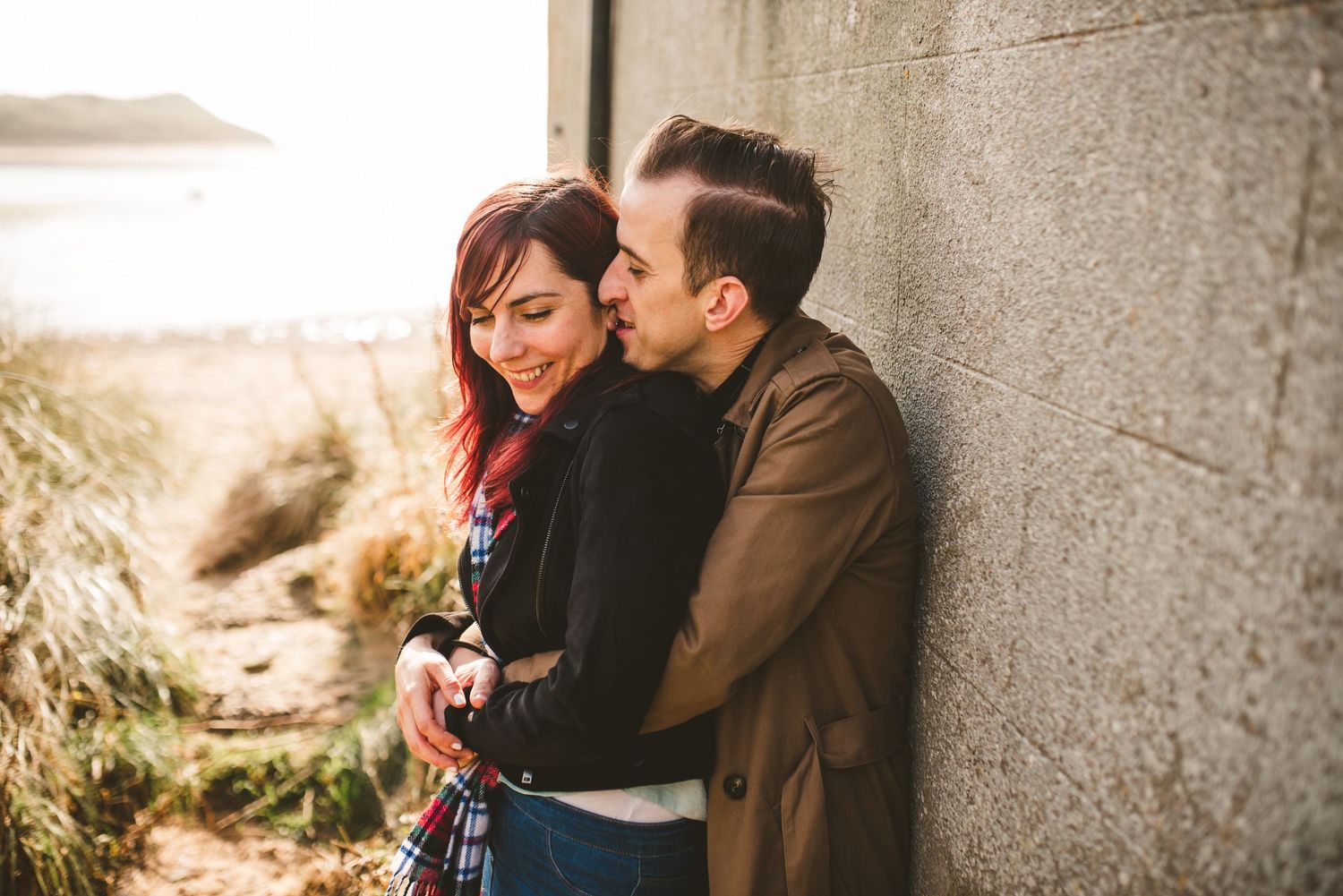 Romantic couple sharing an intimate moment against a concrete wall near golden hour.