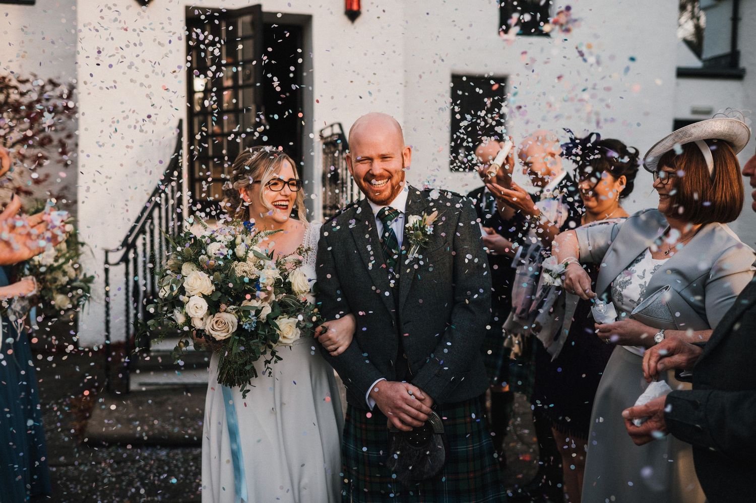 Newlyweds exit their wedding ceremony while guests shower them with confetti.
