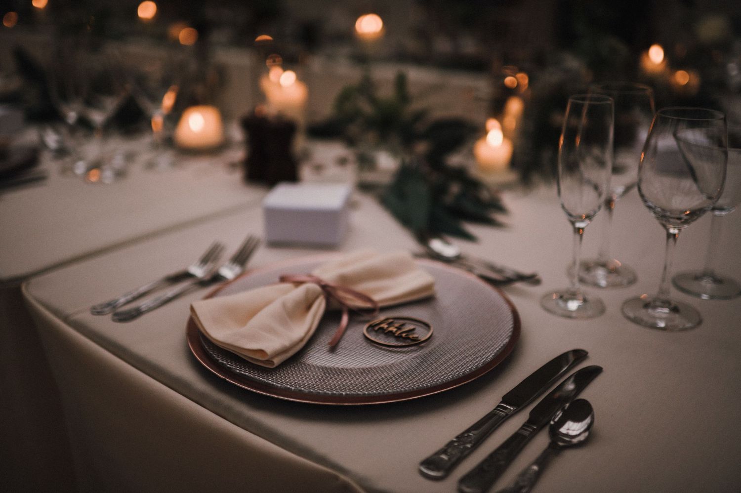 Candlelit wedding table setting with silver cutlery and beige napkin.