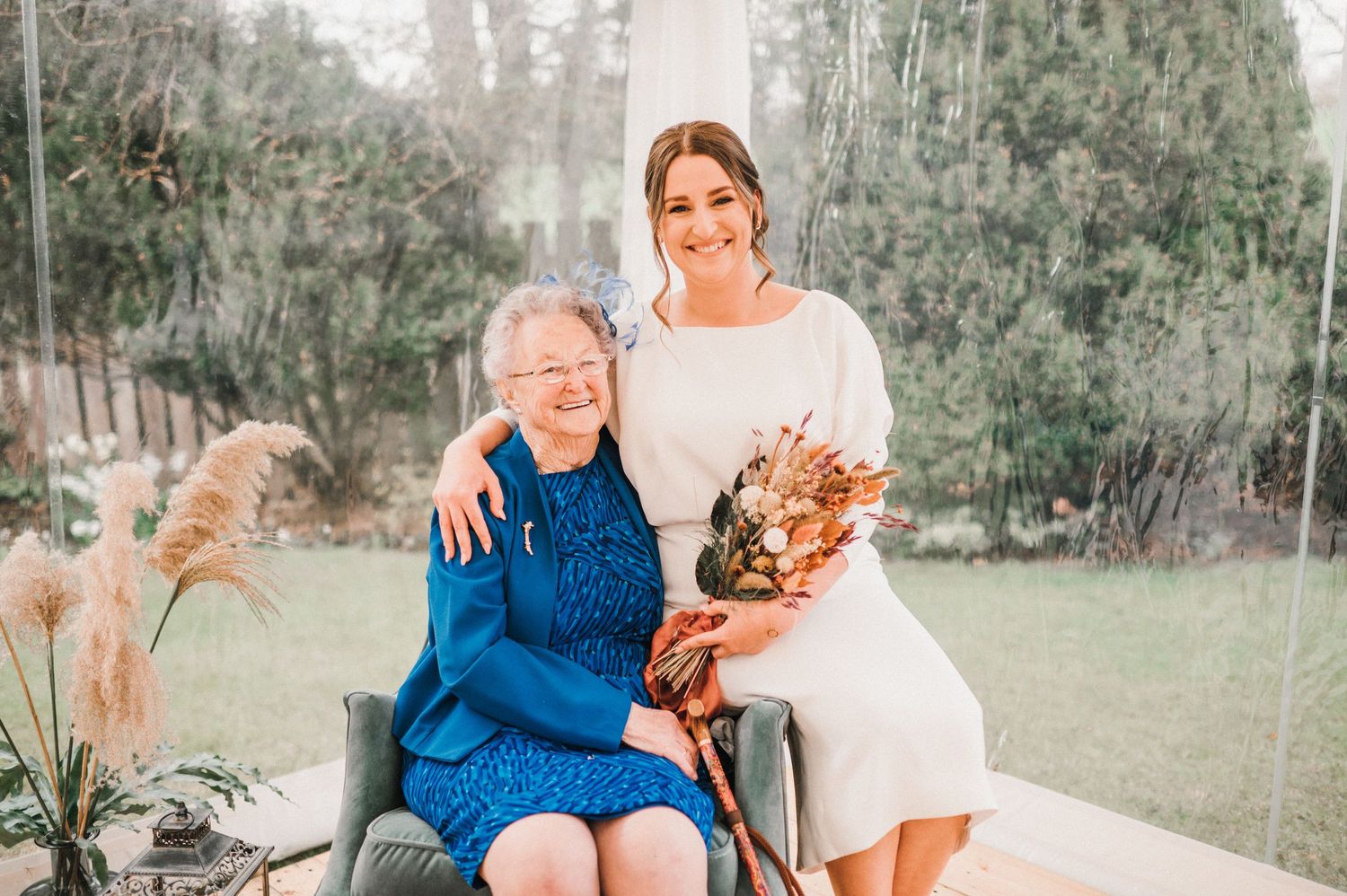 A touching wedding moment in a garden with an elderly woman in bright blue dress.