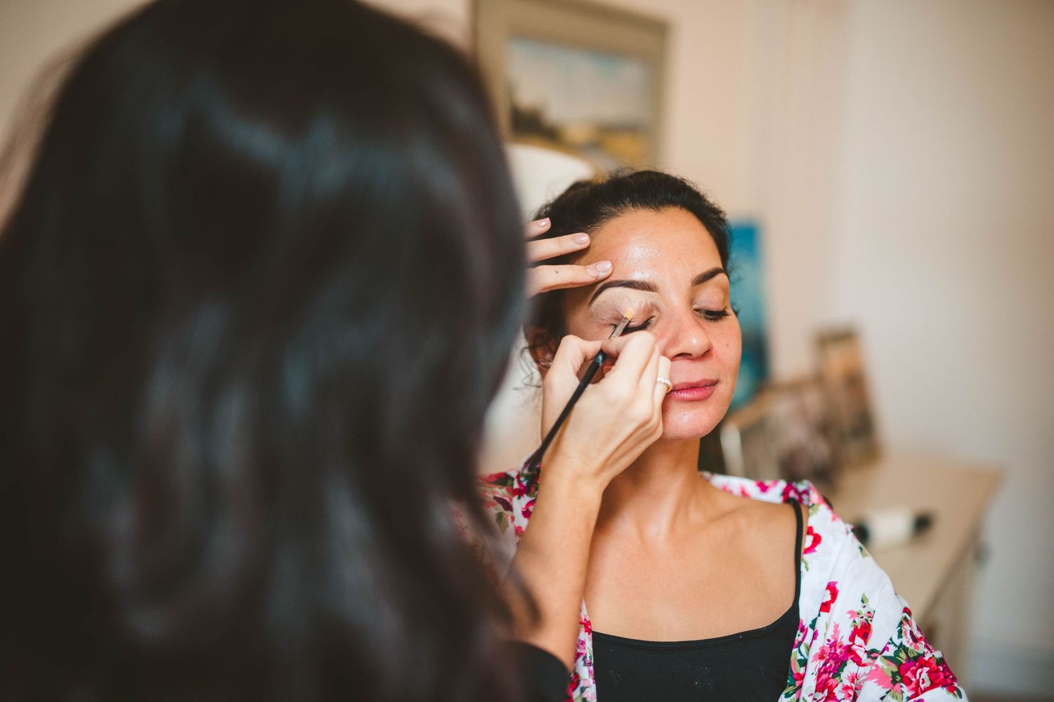 Professional makeup application in progress in a bright indoor setting.
