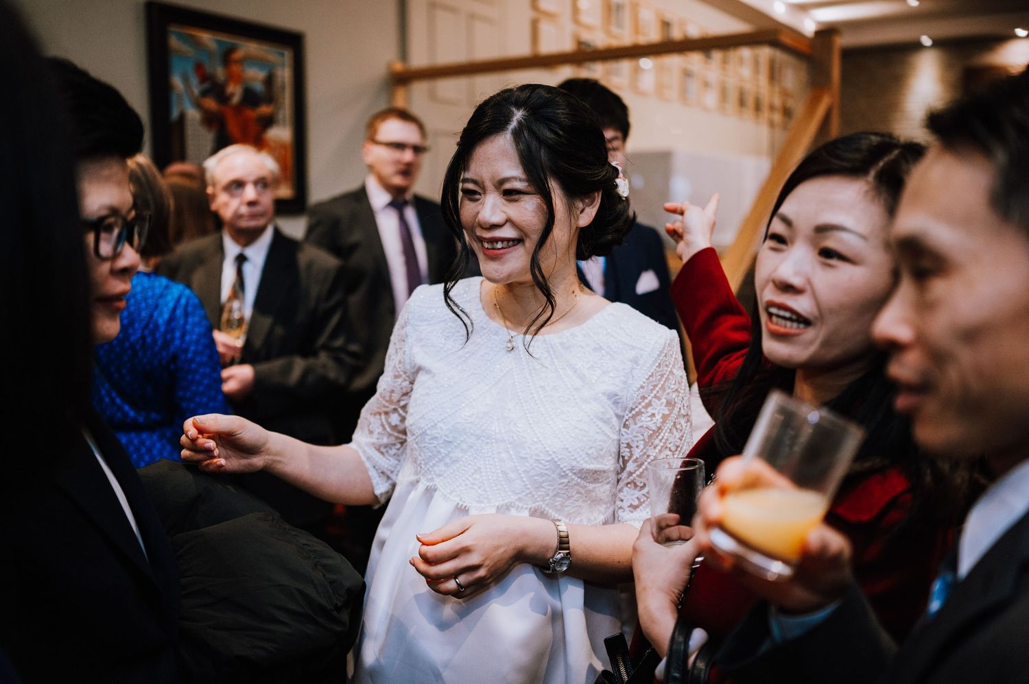 Wedding guests share laughter and conversation during an indoor celebration.