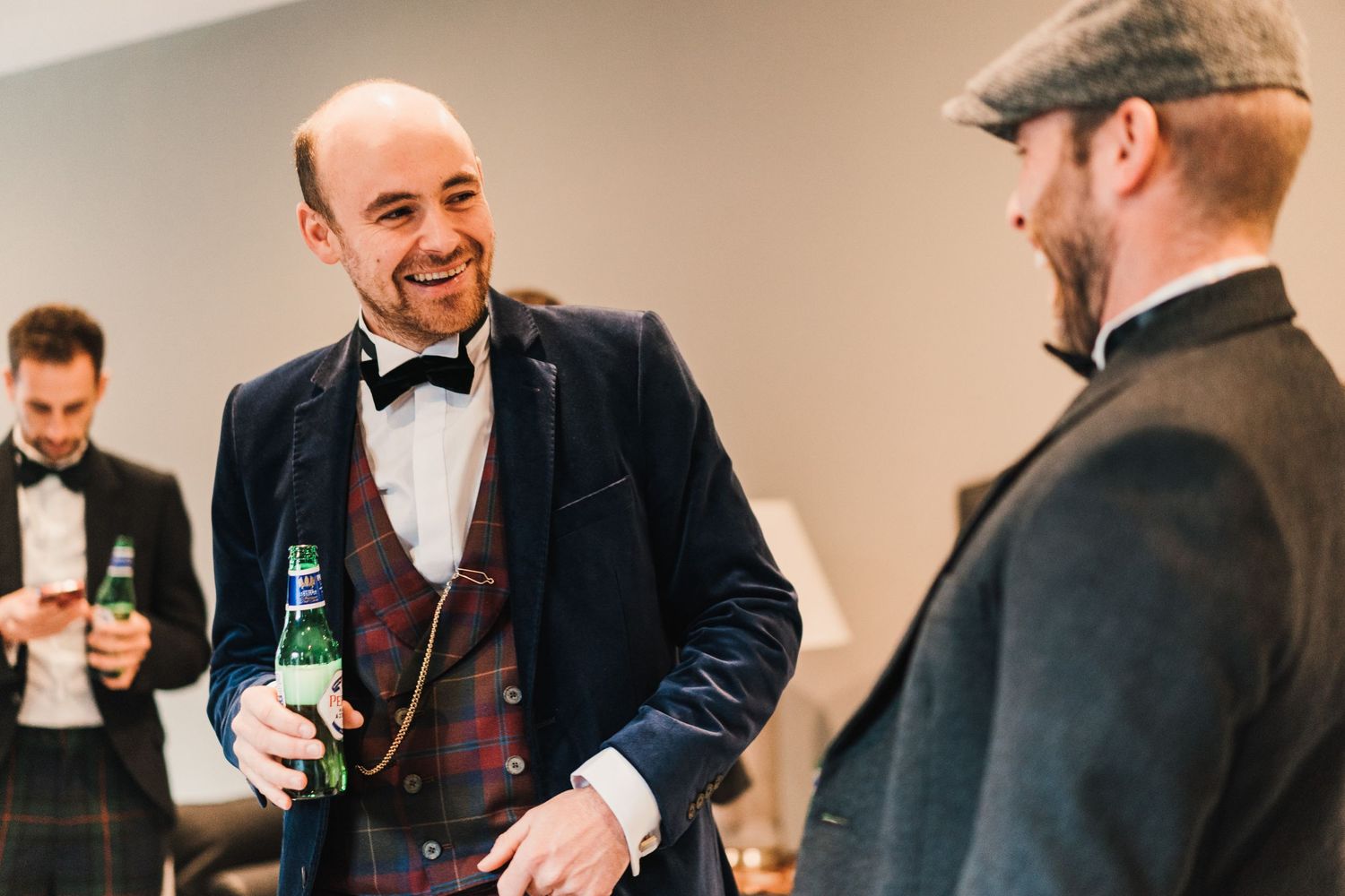 Wedding party members in formal attire share drinks and laughs before the ceremony.