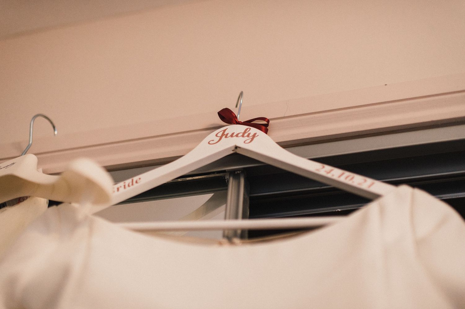 White wedding dress hanger with 'bride' text displayed on a wooden closet rod.