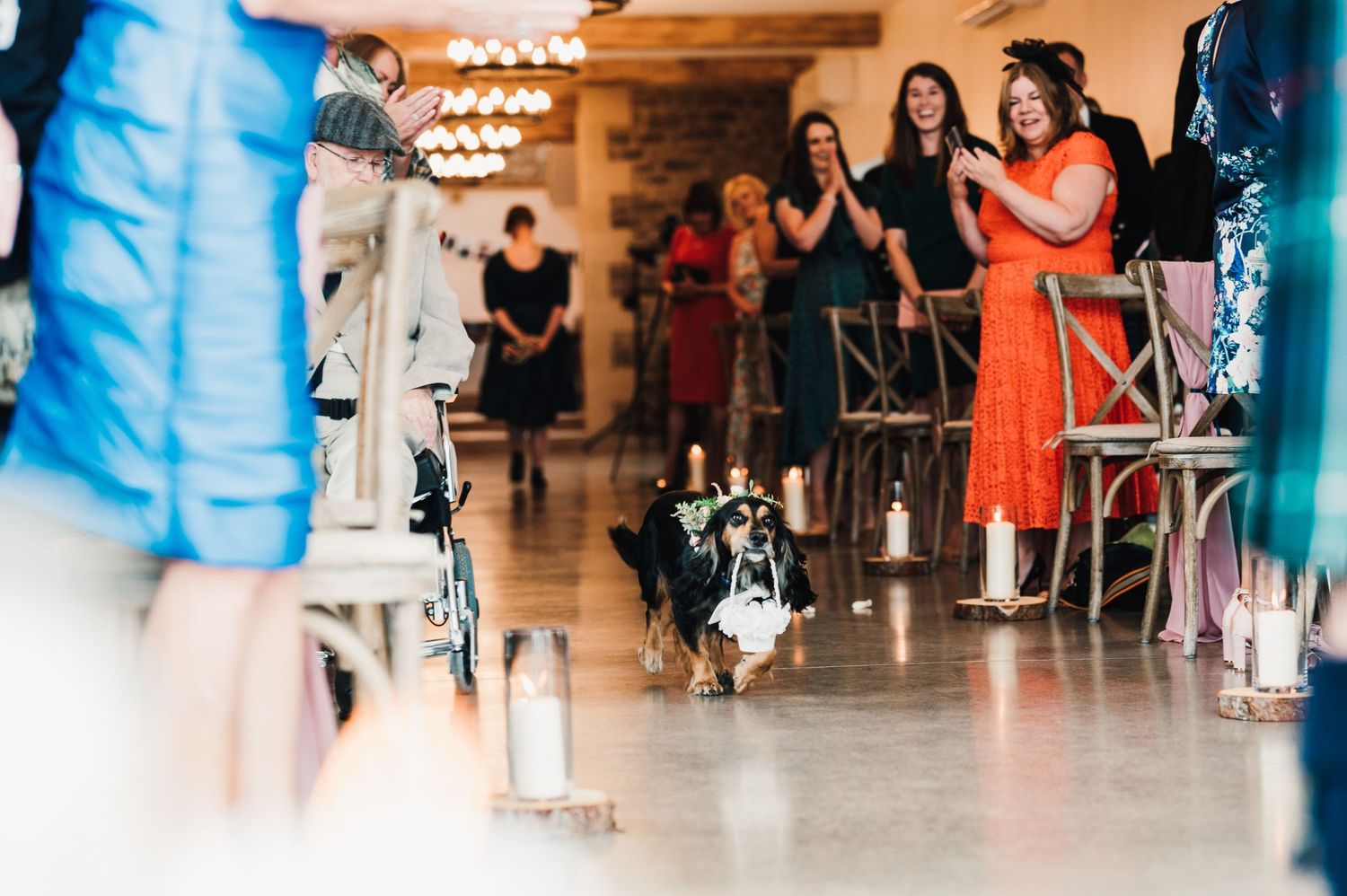 Wedding guests in colorful dresses watching the celebration in an indoor venue.