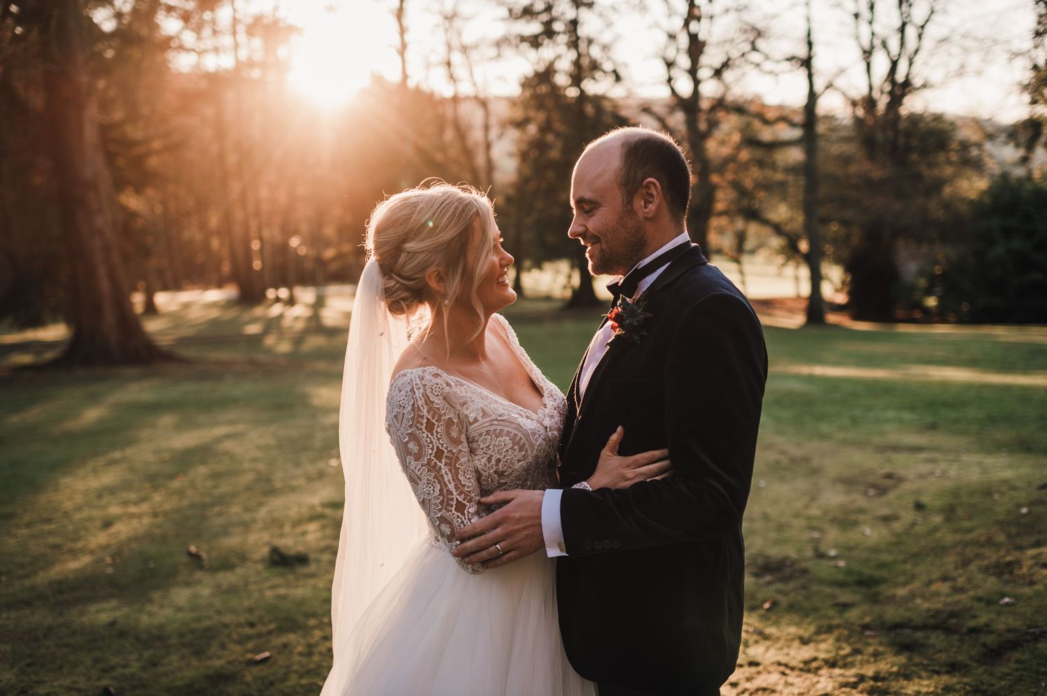 Romantic sunset wedding portrait with couple embracing in warm evening light.