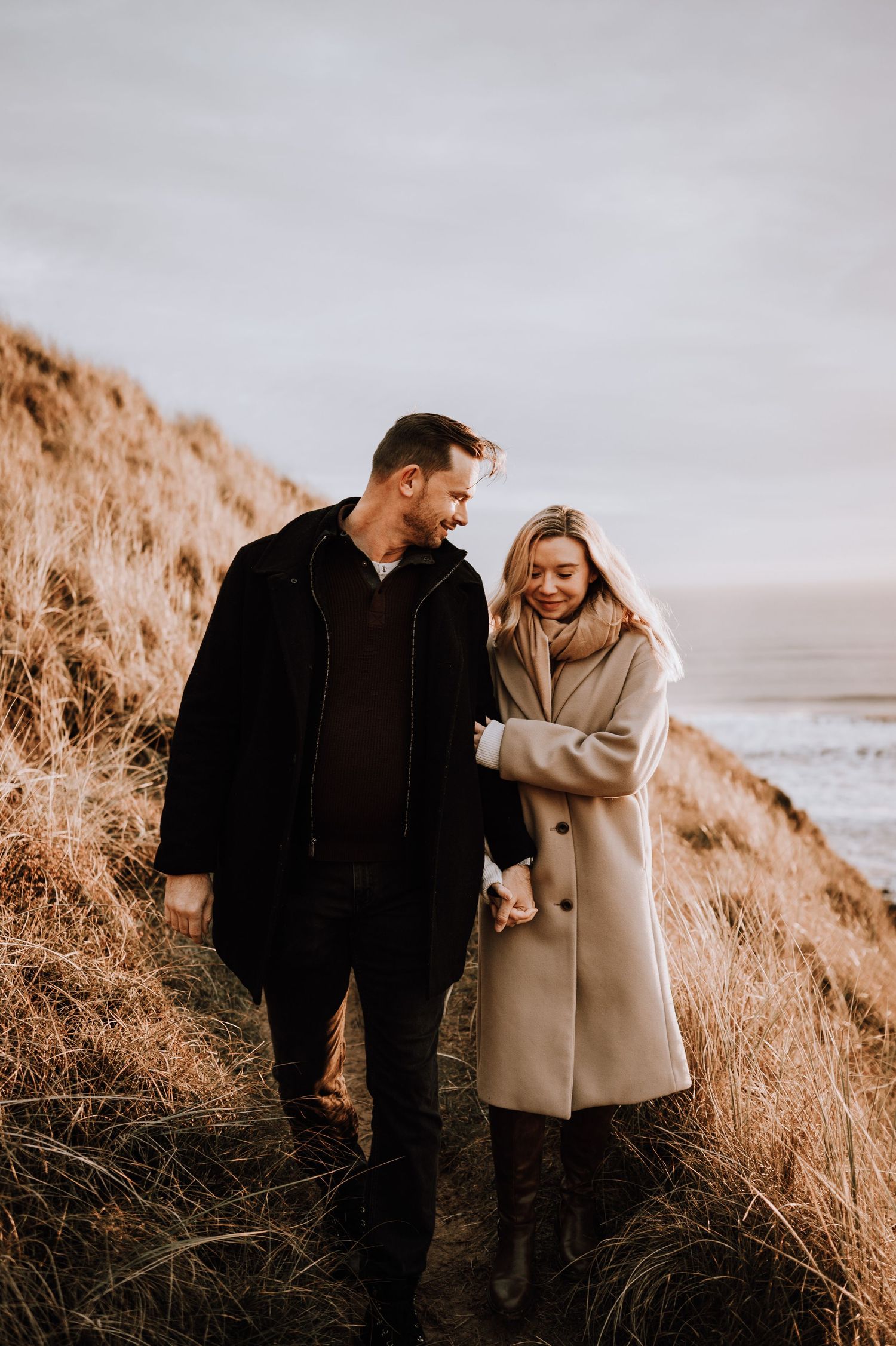 Happy couple walking hand in hand along scenic coastal trail.