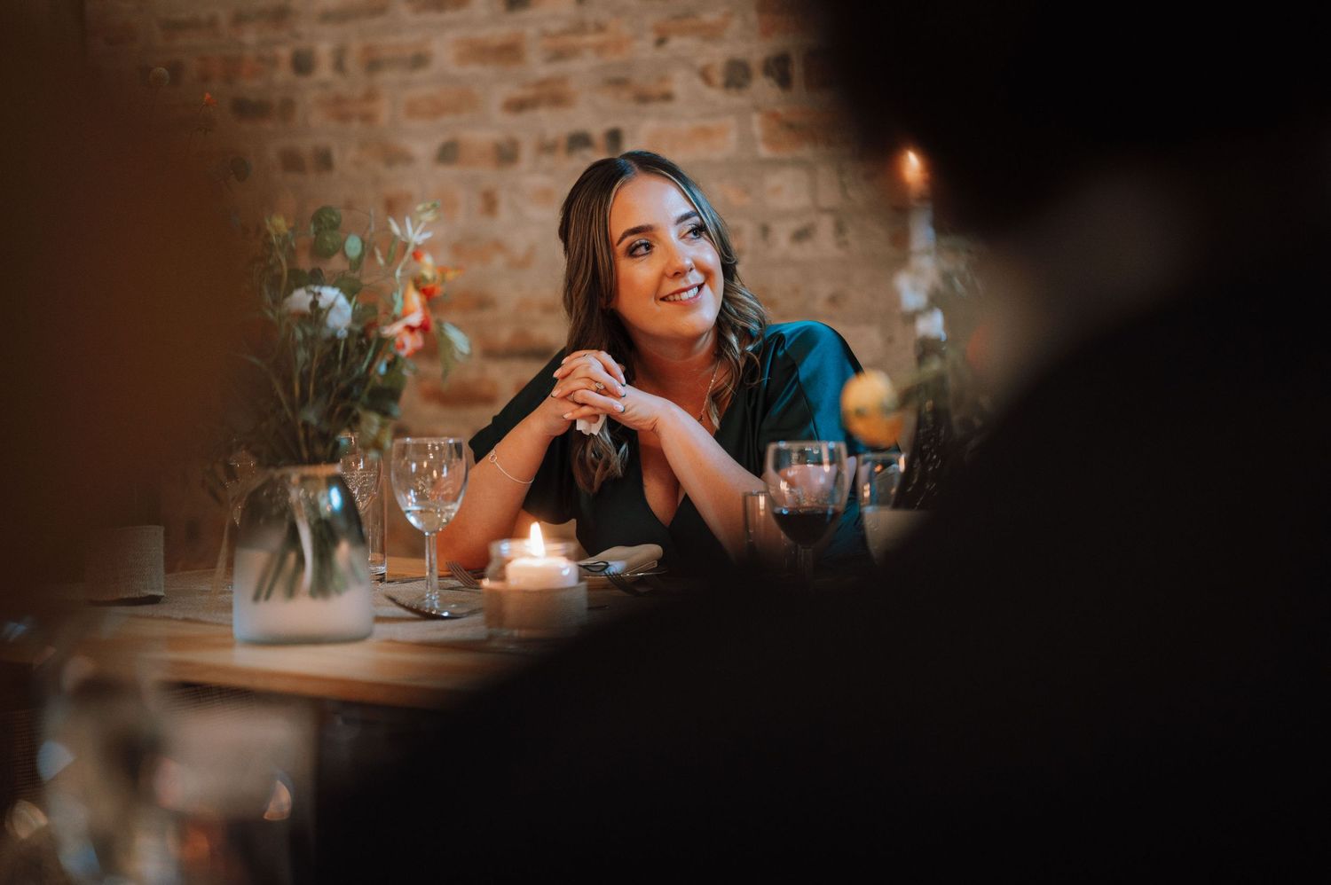 Guest smiles while enjoying candlelit wedding reception dinner.