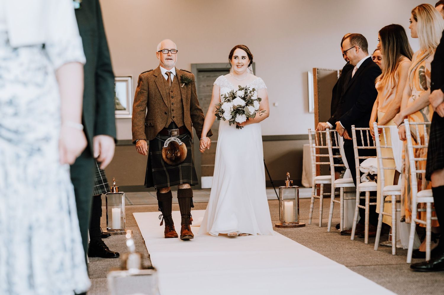 Wedding ceremony space with white chairs and floral arrangements along the aisle. Meldrum House Wedding Photography.