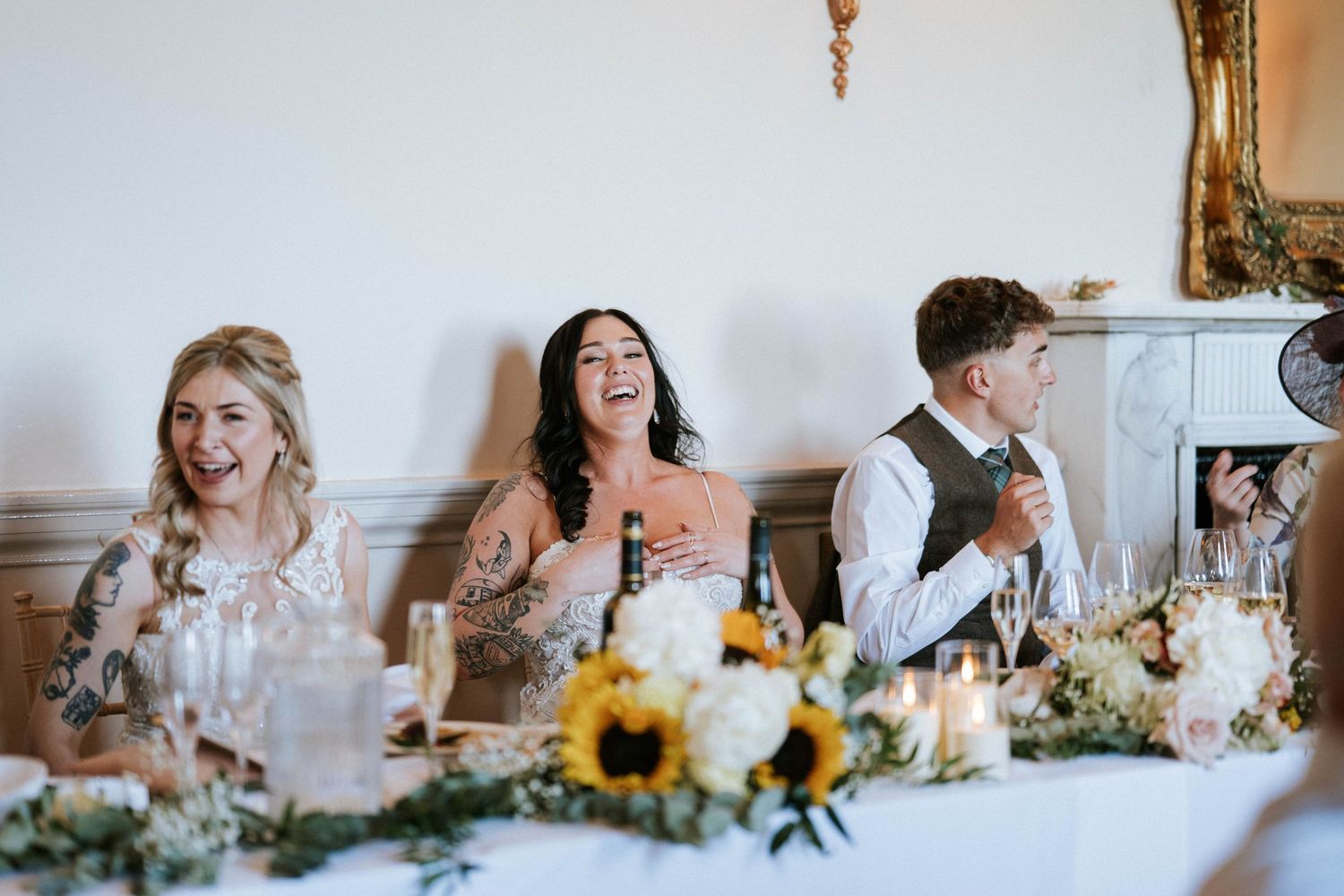 Fasque Castle Wedding Photography. Wedding party members share candid moments at decorated reception table.