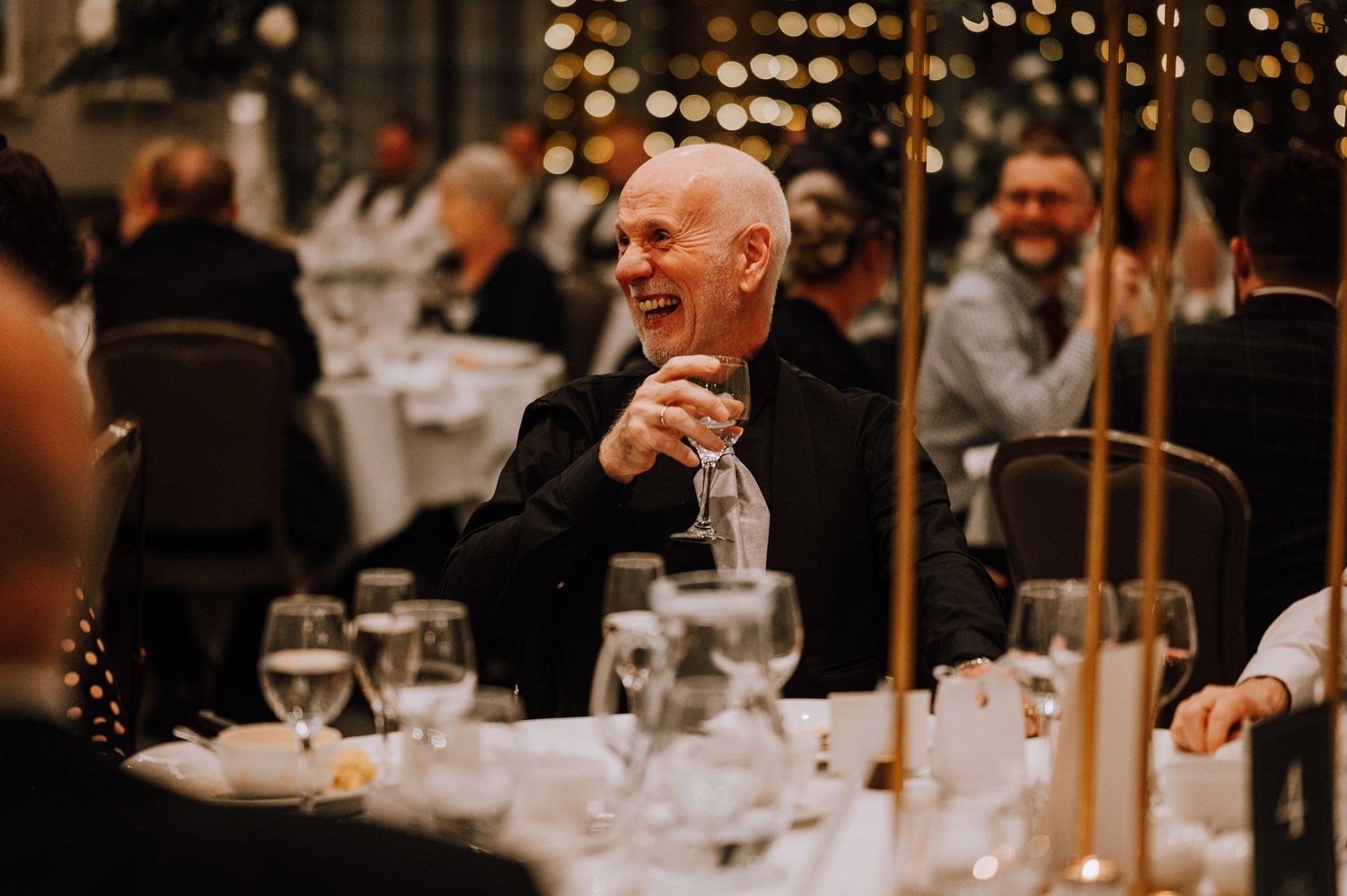Guest sharing laughter and raising a glass during an elegant wedding reception dinner.