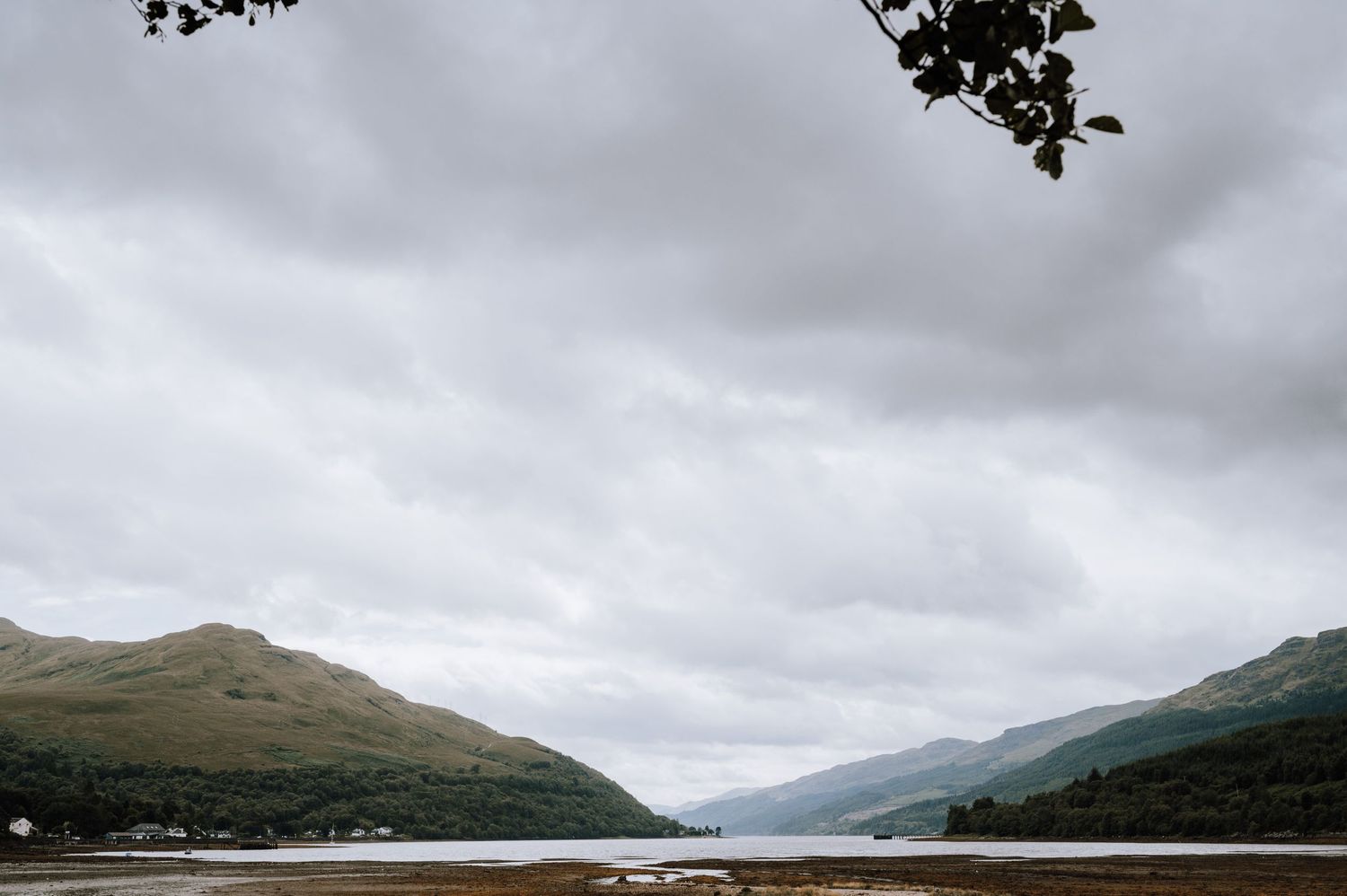 Dramatic cloudy landscape over a Scottish loch with mountains rising on either side.