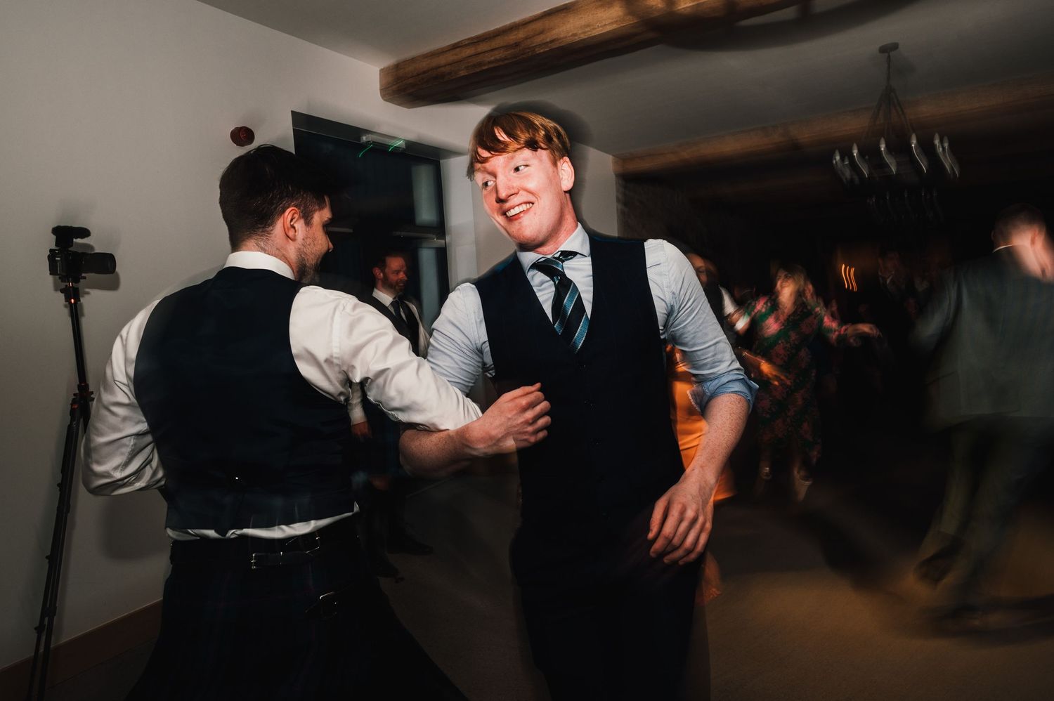 Two guests enjoying lively dancing at a dimly lit indoor celebration.